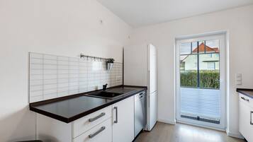 A kitchen with white cabinets, a black countertop, and a window with a view of a house.