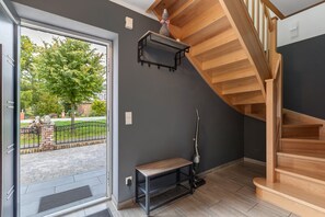 Un interior moderno con una escalera de madera, un banco y vistas al exterior.