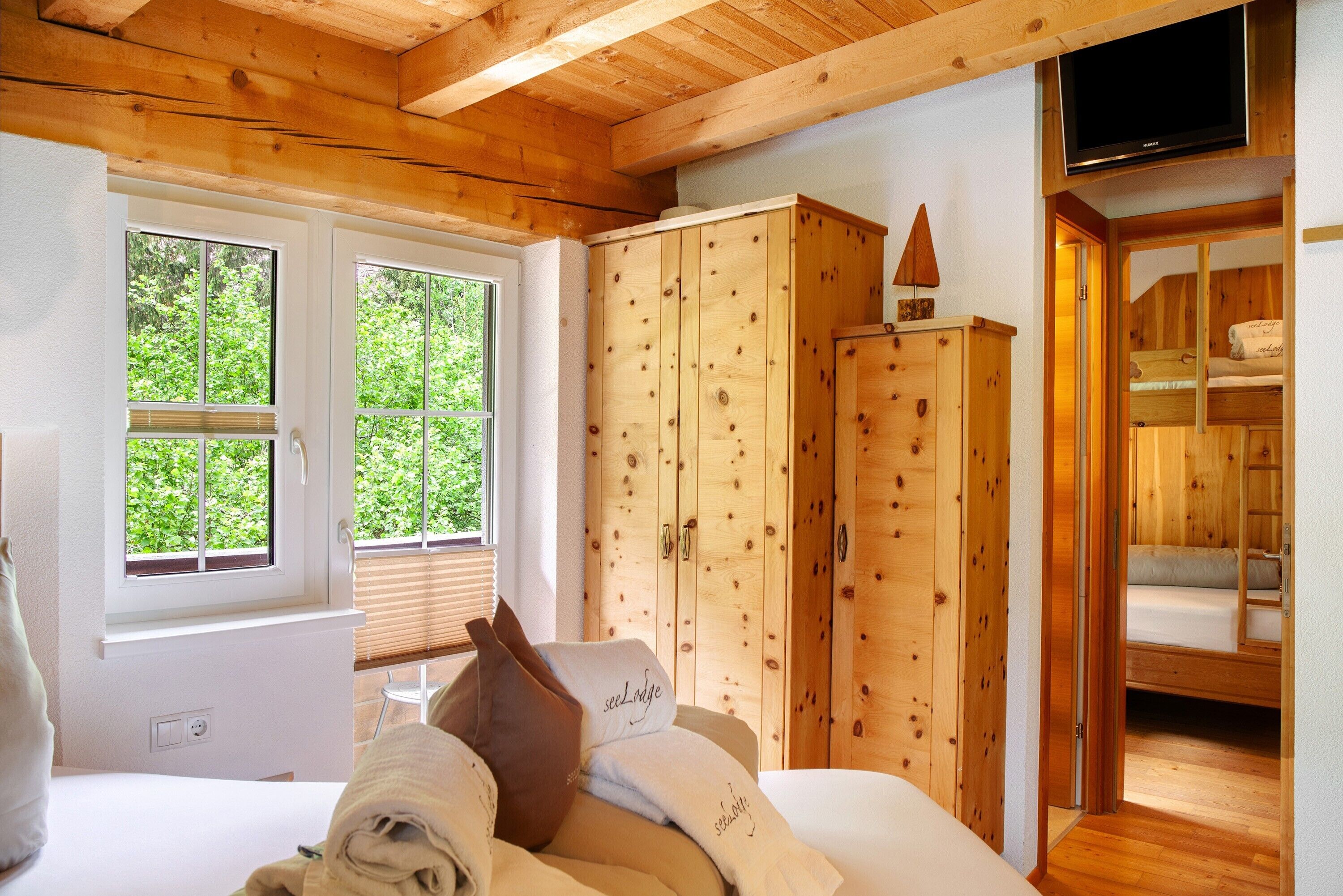 Interior de una cabaña de madera con una cama, un armario y un televisor.