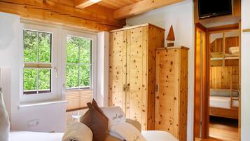 Interior de una cabaña de madera con una cama, un armario y un televisor.