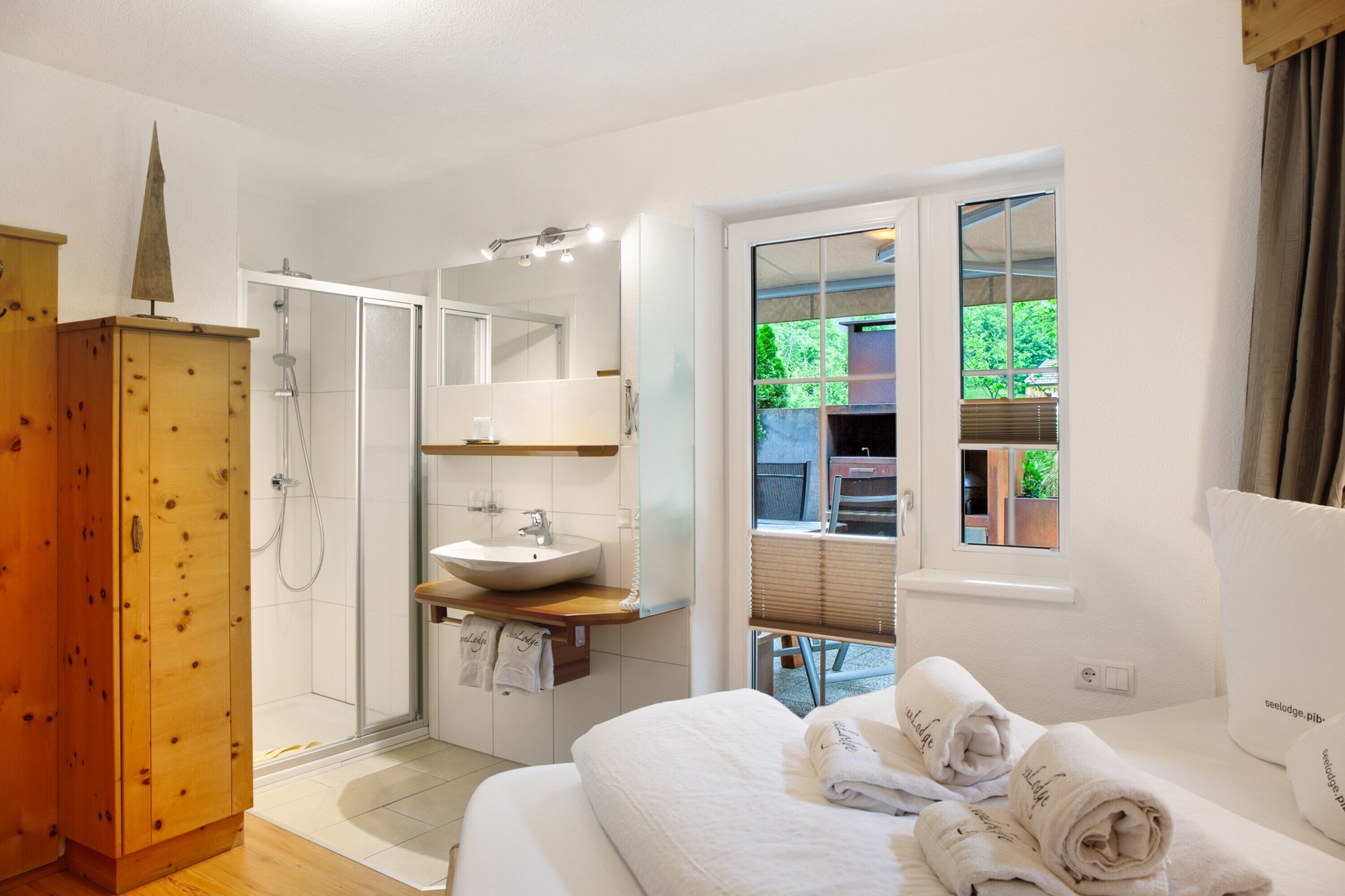 A modern bathroom with a glass shower, a wooden cabinet, a sink, and a large mirror.
