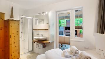 A modern bathroom with a glass shower, a wooden cabinet, a sink, and a large mirror.