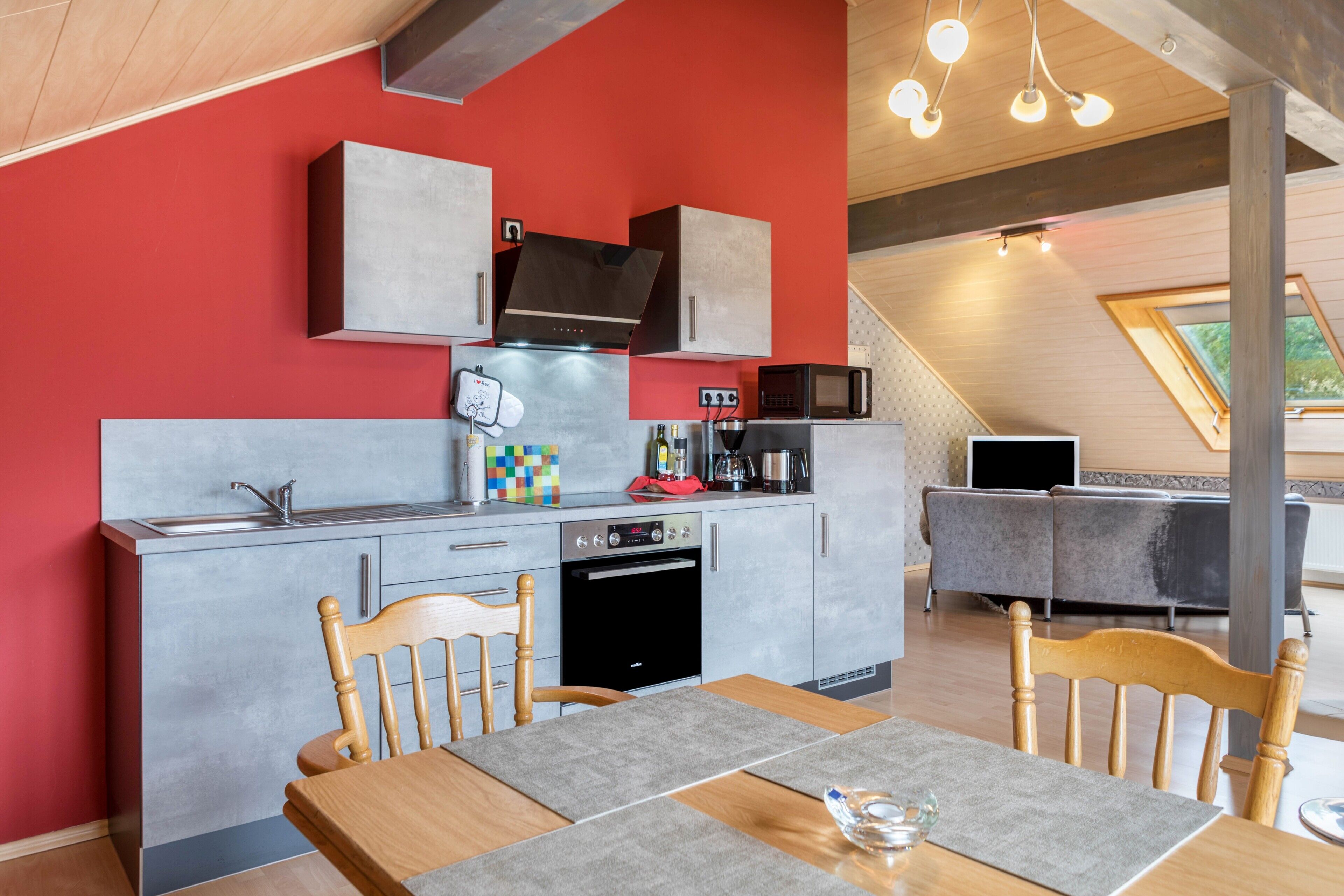 Una cocina moderna con gabinetes grises, un microondas, una estufa y un lavamanos. Hay una mesa de comedor con sillas.
