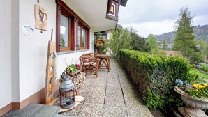 A wooden outdoor seating area with a table and chairs, a lantern, and a potted plant. - Haus Kurparkblick – Apartment Am Schluchtensteig with Wi-Fi (Todtmoos)