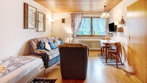 A cozy living room with a sofa, a chair, a table, and a TV. - Haus Kurparkblick – Apartment Am Schluchtensteig with Wi-Fi (Todtmoos)