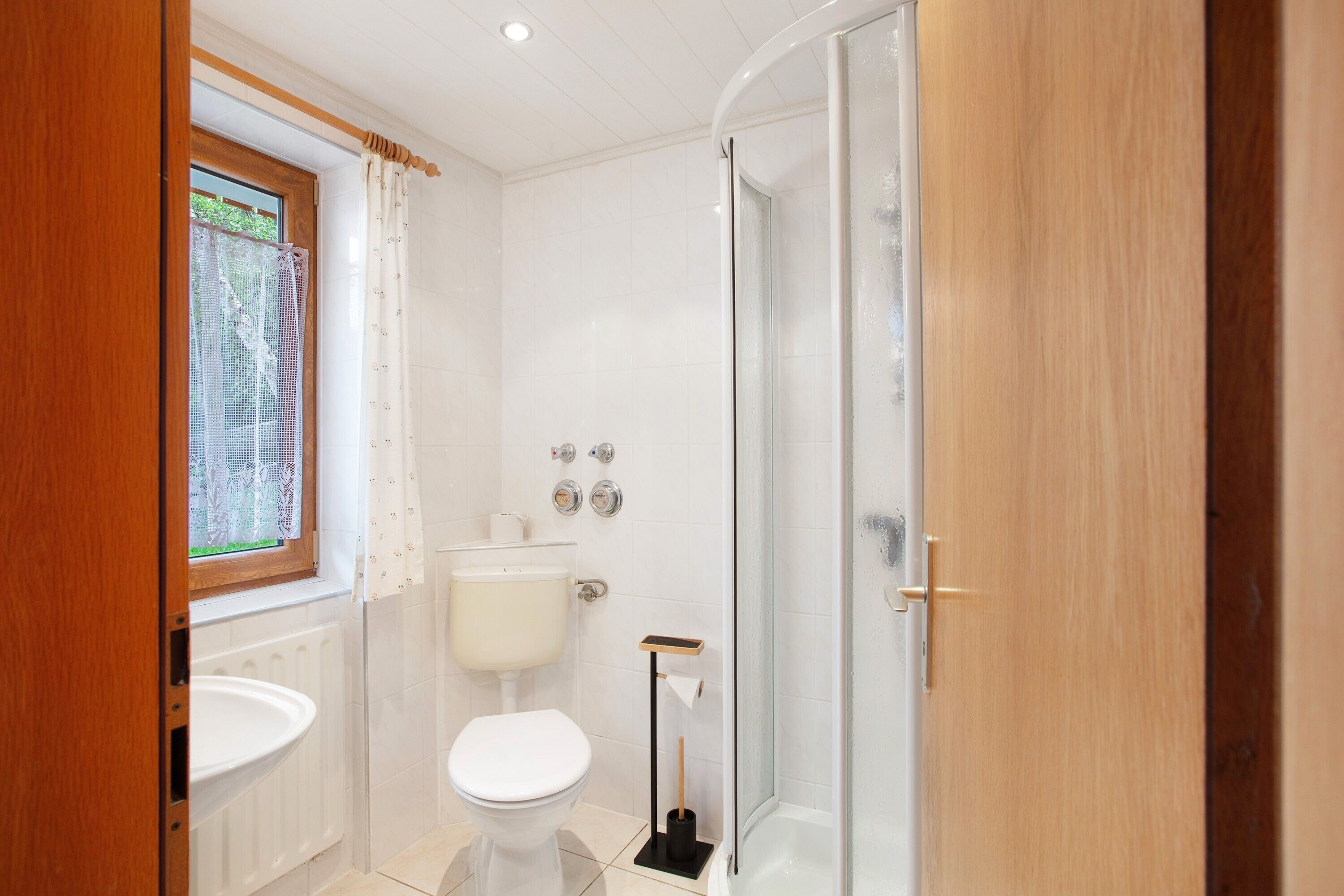 Een moderne badkamer met toilet, wastafel en douche.