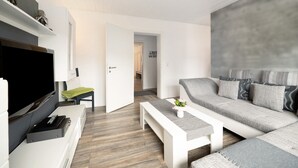 Ein modernes Wohnzimmer mit Fernseher, einer Couch, einem Couchtisch und einer Bank.