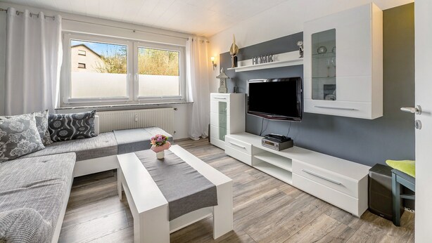 Ein modernes Wohnzimmer mit einer Couch, einem Fernseher und Einbauschränken.