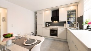 Eine moderne Küche mit weißen Schränken, einem eingebauten Backofen und einem Essbereich mit gedecktem Tisch für zwei Personen.