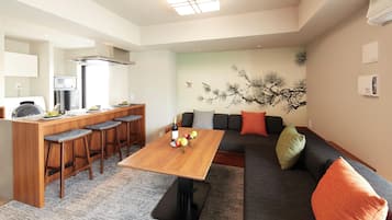 A modern living space with a kitchen area, a dining table, and a sofa with cushions.