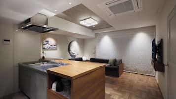 A modern kitchen with a central island, a dining area with a sofa, and a large window.