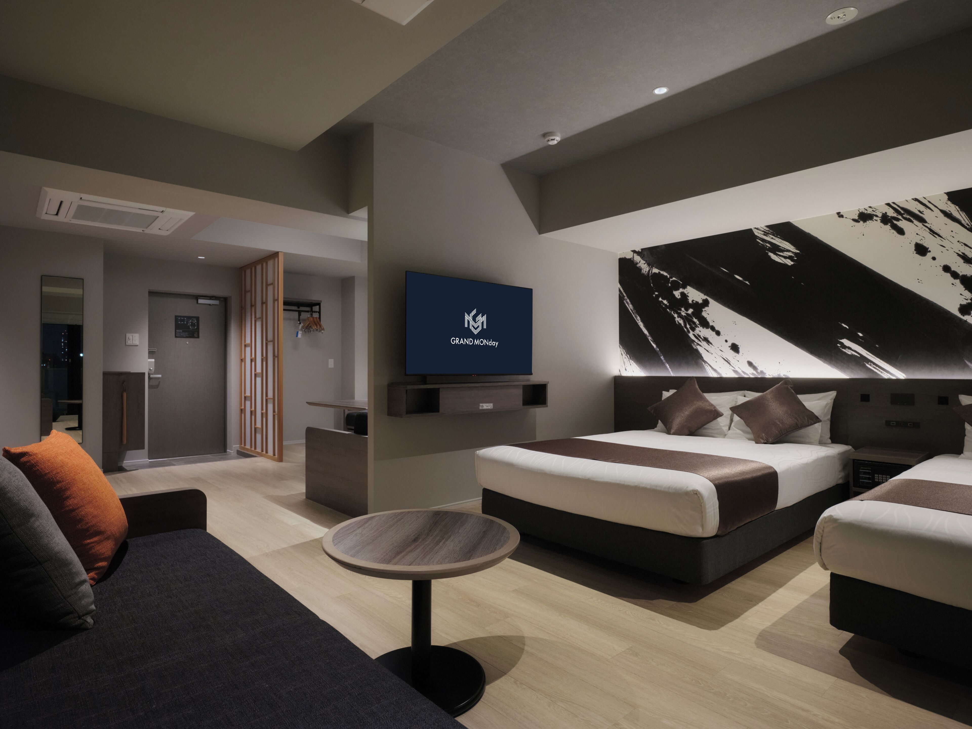 A modern hotel room with a large bed, a smaller bed, a sofa, a TV, and a painting on the wall.