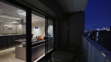 Un espace de vie moderne comprenant une cuisine, un coin repas et un balcon offrant une vue sur la ville.