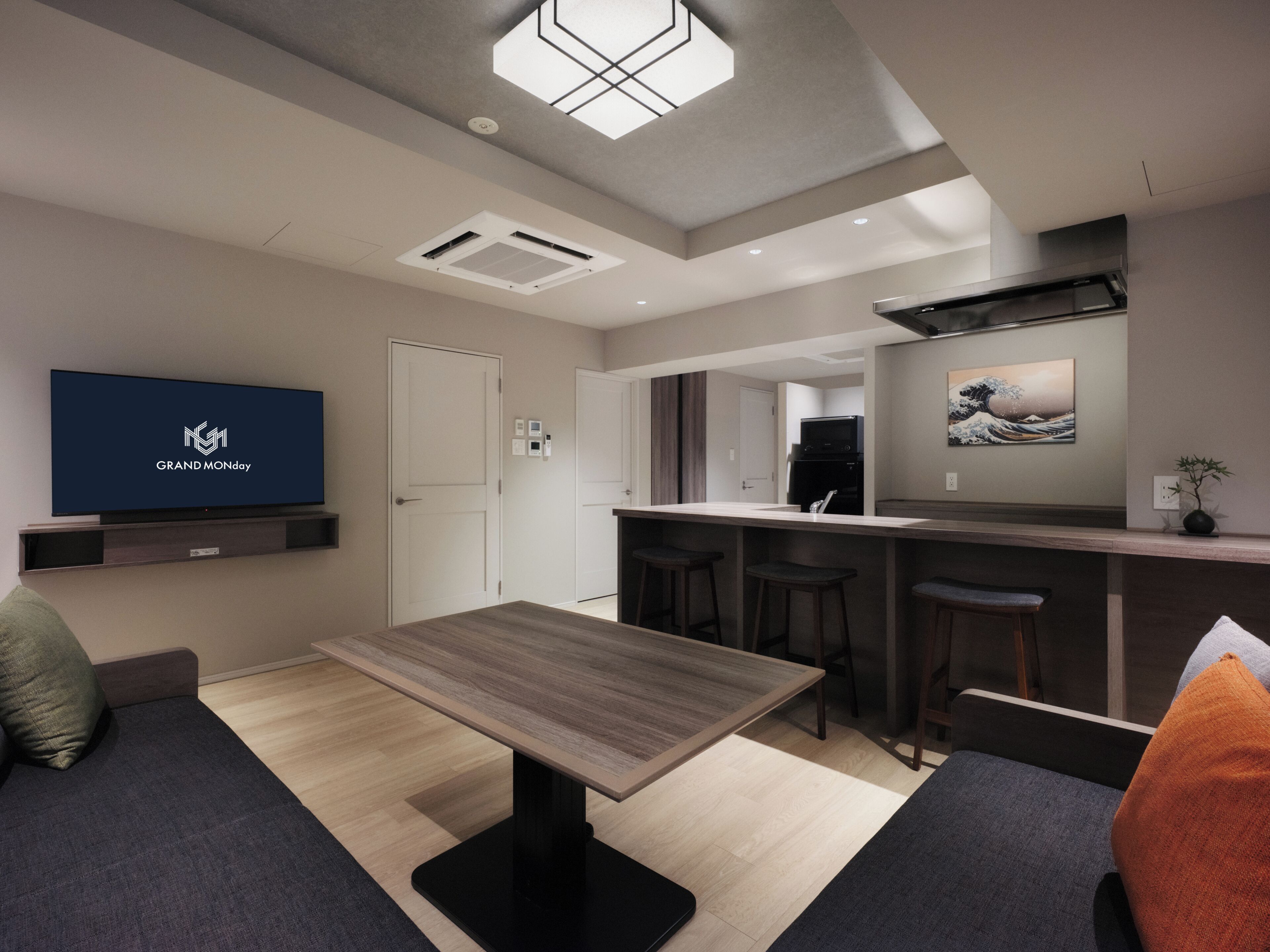 Una sala de estar moderna con televisor de pantalla plana, una mesa de comedor y una zona de cocina con taburetes de bar.