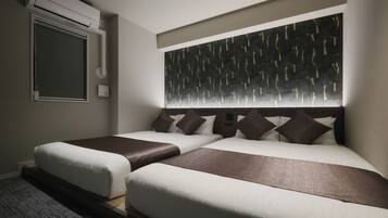 A hotel room with two beds, a large abstract wall art piece above the beds, an air conditioning unit mounted on the wall, and a window with a closed blind.