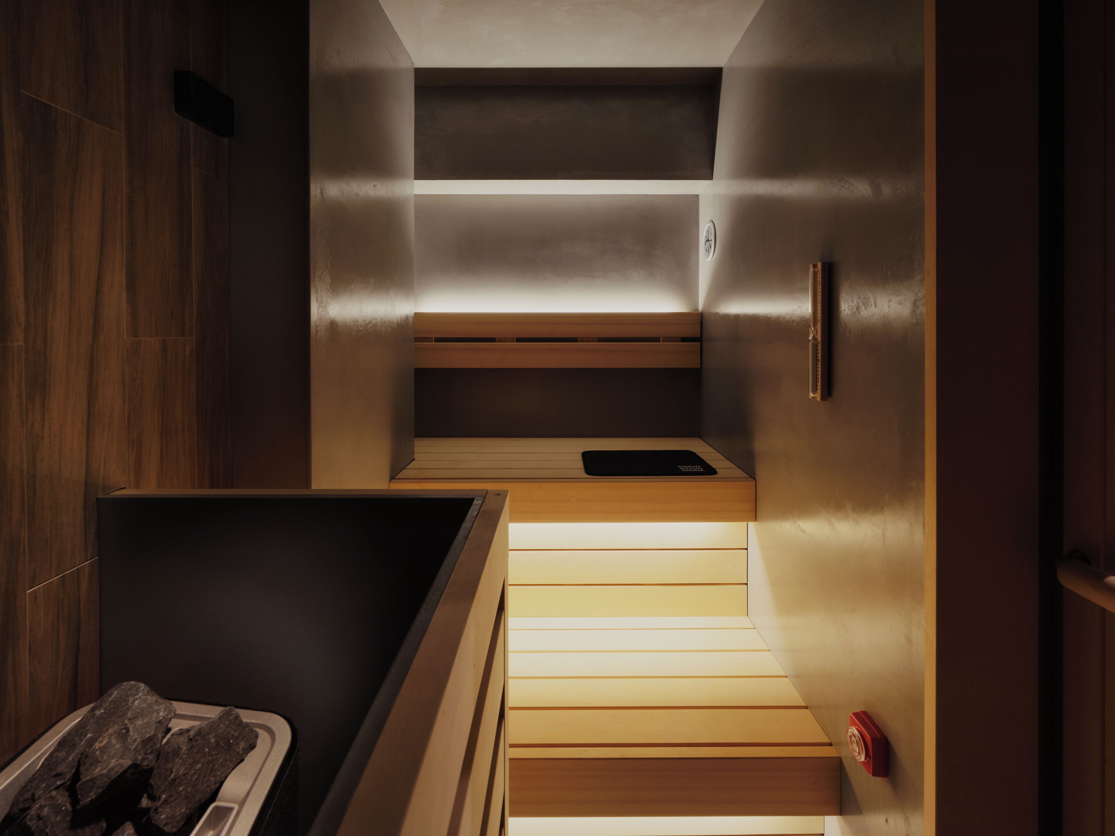 A modern sauna with wooden benches and a bench at the bottom.