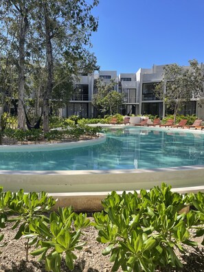 A modern hotel with a swimming pool, surrounded by lush greenery and trees. - Tulum Sweet condo with private pool.  Enjoy nature in the Maya jungle! (Tulum)