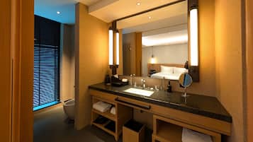 A modern hotel bathroom with a granite countertop, a large mirror, and a white sink.