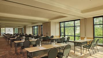 A large conference room with multiple tables and chairs, large windows with a view of trees, and a sign reading "TENTREM".