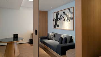 A modern room with a round table, a sofa, and a large abstract painting on the wall.