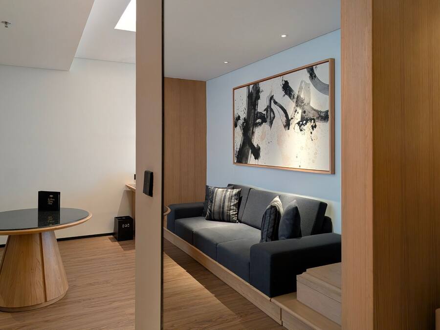 A modern room with a round table, a sofa, and a large abstract painting on the wall.