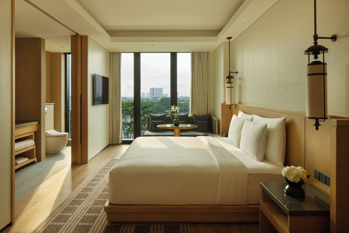 A hotel room with a large bed, a small round table, a sofa, and a TV.