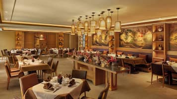 A spacious restaurant with multiple dining tables, warm lighting, and traditional decor.