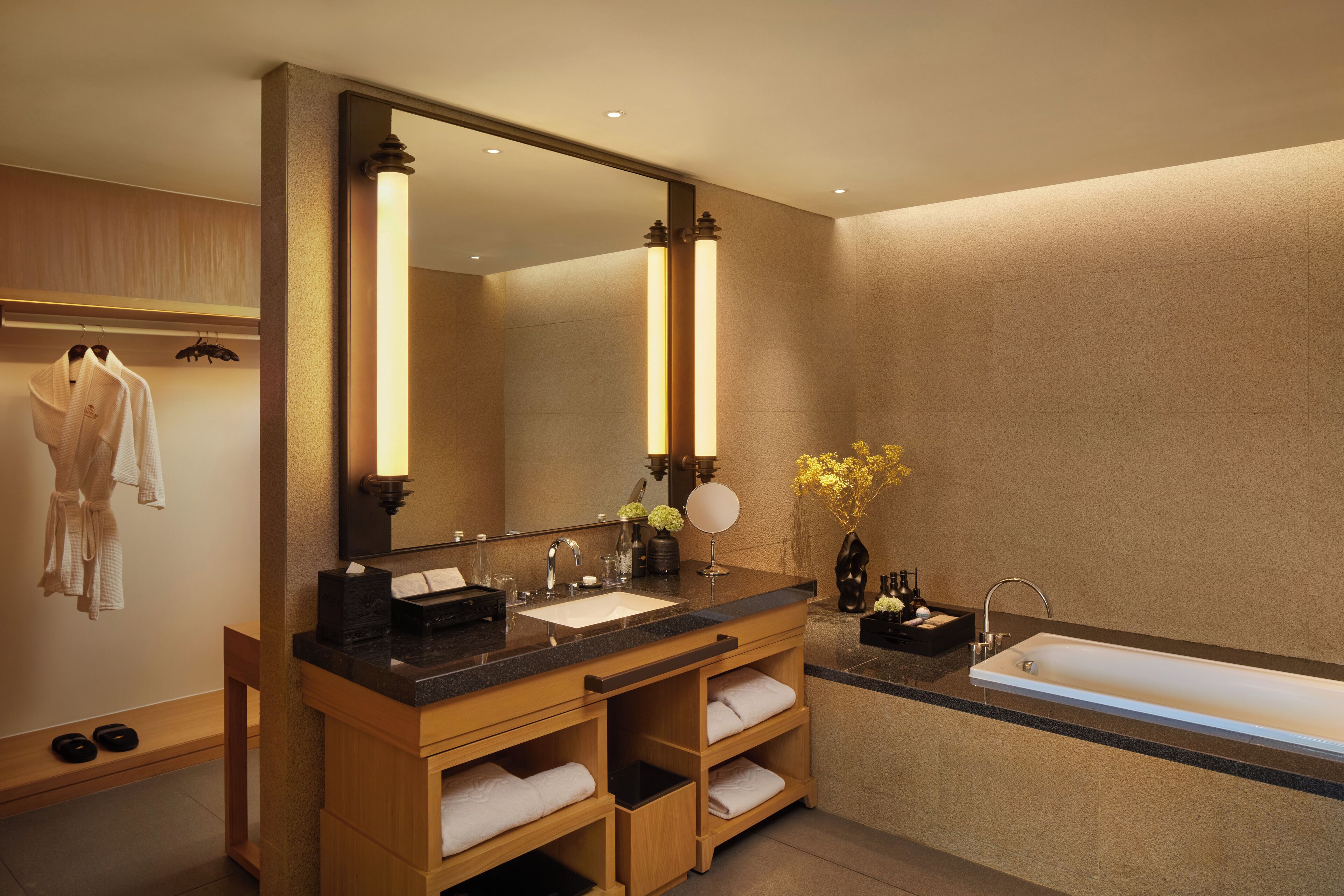 A modern bathroom with a large mirror, wooden vanity, dual sinks, and a bathtub.