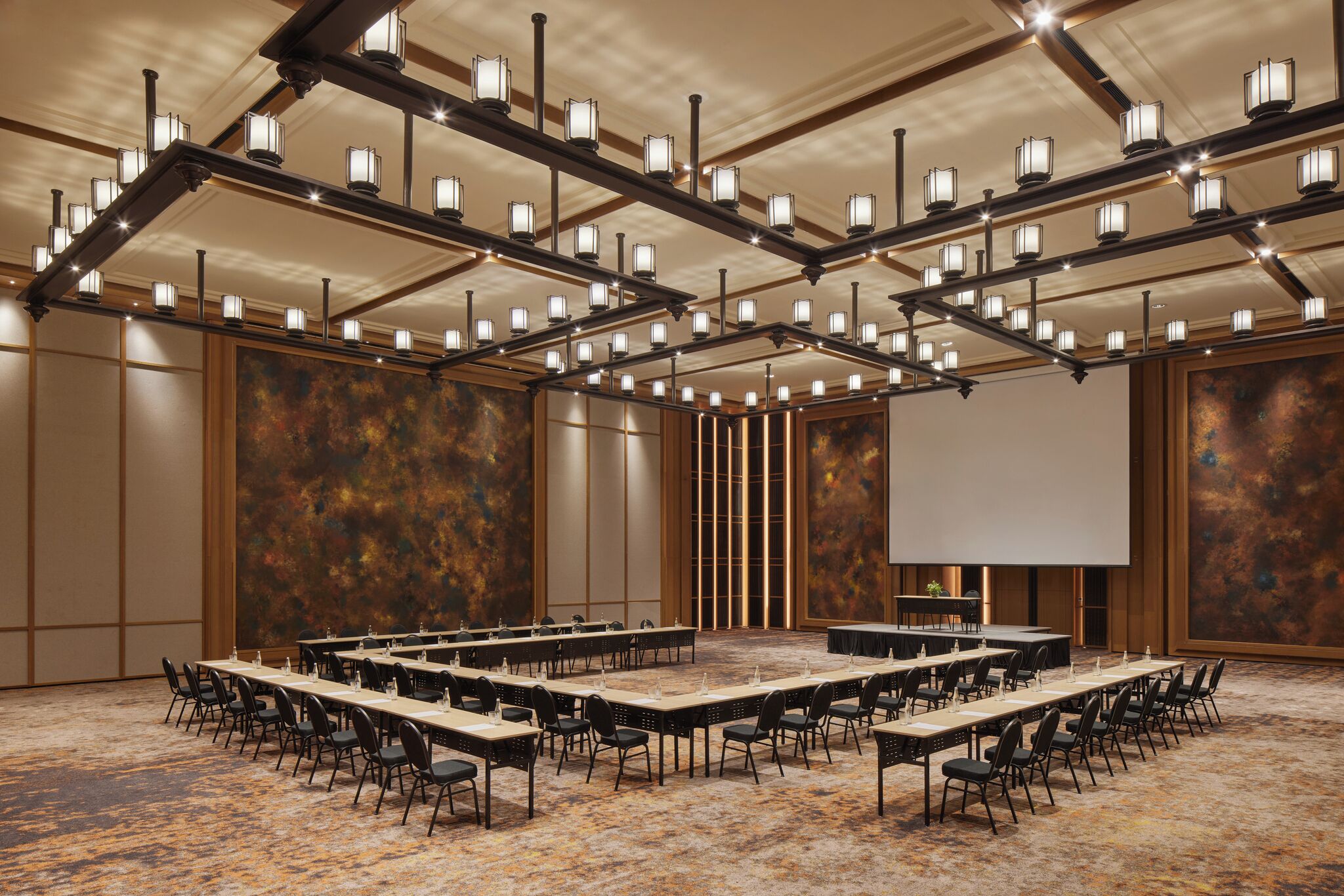 A conference room with a long table, chairs, and a projector screen.
