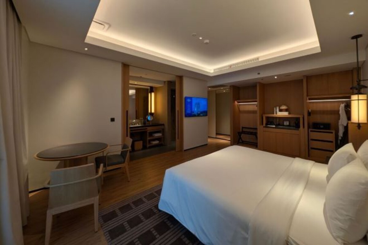 A hotel room with a bed, a desk, a chair, a TV, and a wardrobe.