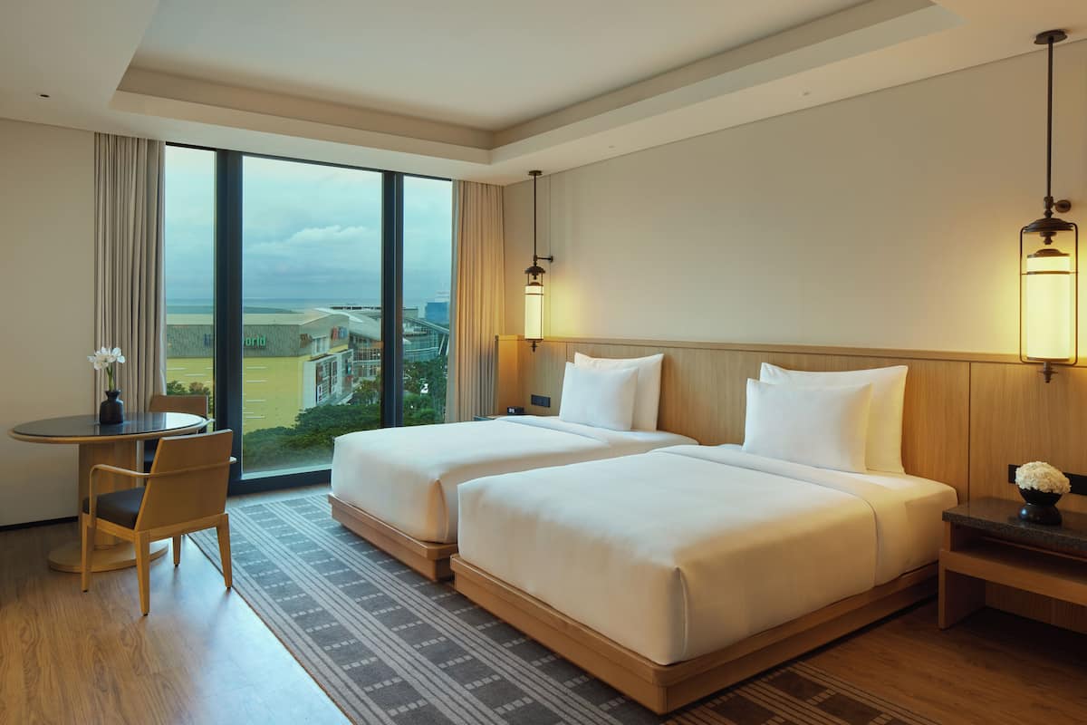 A hotel room with two beds, a desk, and a chair.