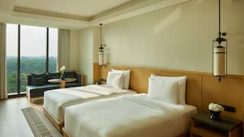 Habitación de hotel con dos camas, un sofá, una mesita y vistas al exterior.
