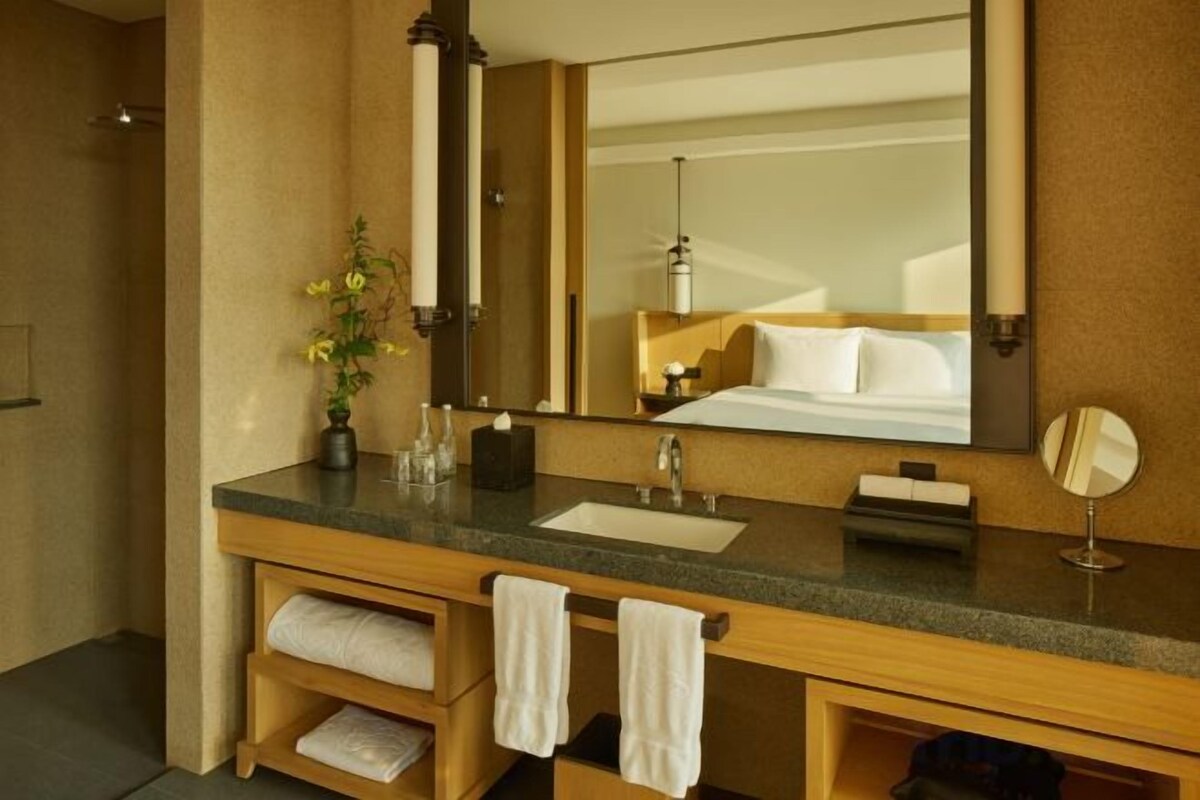 Une salle de bain avec un comptoir en granit, un grand miroir, un lavabo et un porte-serviettes.