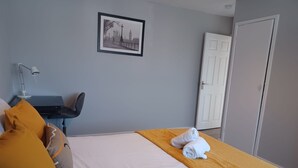 Hotellihuone, jossa on sänky, työpöytä, tuoli, lamppu ja ovi.