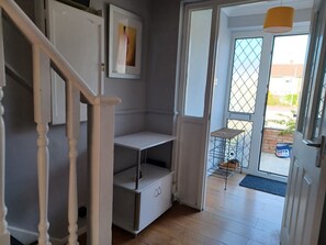 Un escalier menant à un palier avec une porte blanche, un tableau encadré accroché au mur et une petite table à ossature métallique placée à l’extérieur.