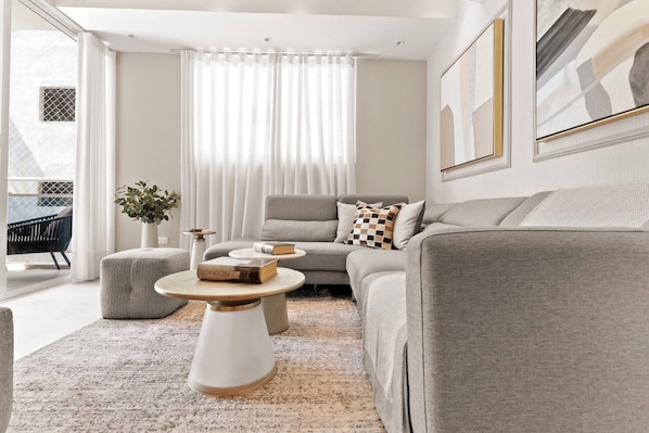 A modern living room with a grey sofa, round coffee table, and a potted plant.