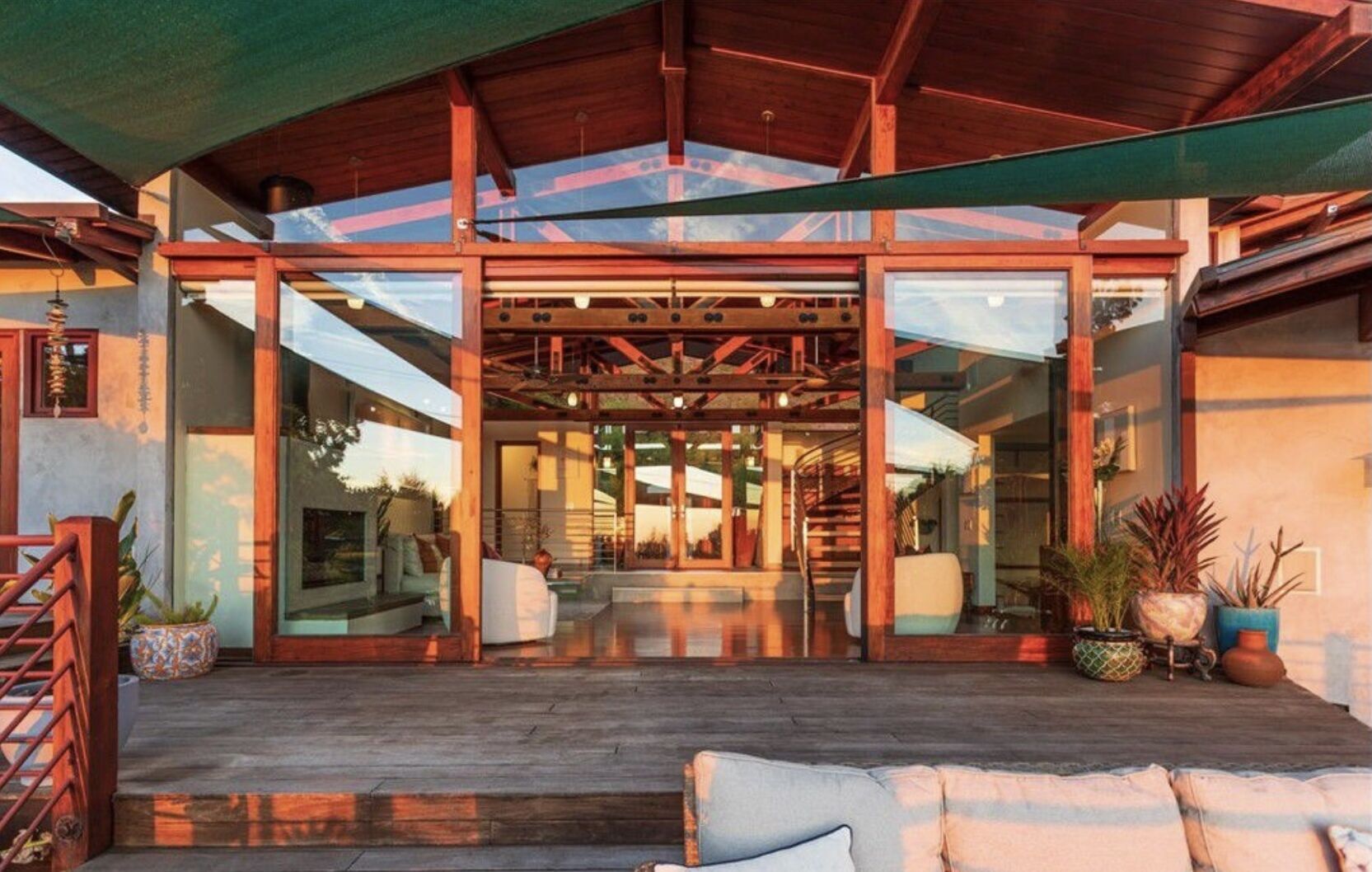 A modern house with a spacious patio, large glass doors, and a wooden deck.