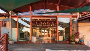 Una casa moderna con un patio amplio, puertas de cristal grandes y una terraza de madera.