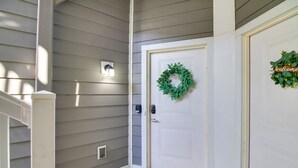 Une entrée de maison avec une porte blanche, une couronne verte et une pancarte de bienvenue.