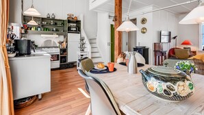 Eine moderne Küche mit weißen Schränken, eine Essecke mit Tisch und Stühlen sowie eine Treppe, die in eine andere Ebene führt.