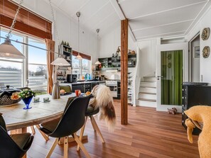 Une cuisine moderne avec un plancher en bois, un coin repas avec une table et des chaises, et une vue sur l’extérieur.