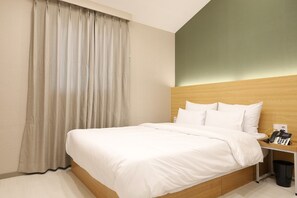 A hotel room with a bed, a nightstand, a telephone, and a trash bin.