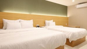 Une chambre d’hôtel avec deux lits, une tête de lit en bois, un climatiseur fixé au mur et une petite table.