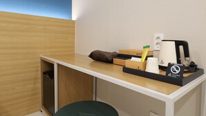 Un bureau d’hôtel avec une machine à café, un panneau « Interdiction de fumer » et une boîte de mouchoirs.