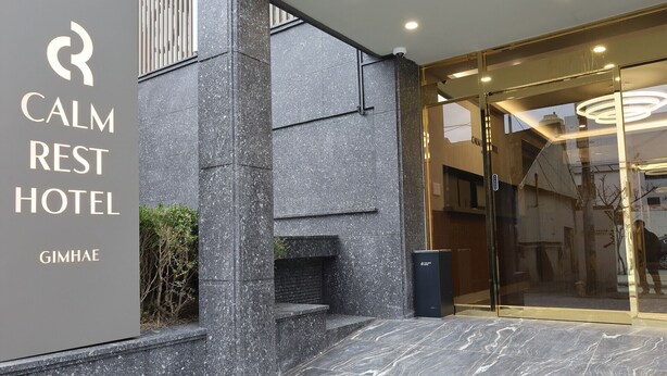 L’extérieur de l’hôtel Calm Rest, doté d’un design moderne, se caractérise par une façade en pierre et une entrée en verre.