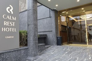 The exterior of the Calm Rest Hotel with a modern design, featuring a stone facade and a glass entrance. - CALM REST HOTEL GIMHAE (Gimhae)