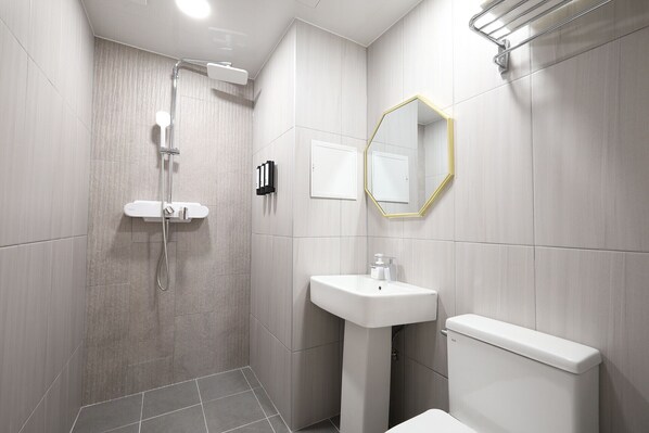 A modern bathroom with a shower, sink, toilet, and a mirror with a gold frame. - CALM REST HOTEL GIMHAE (Gimhae)