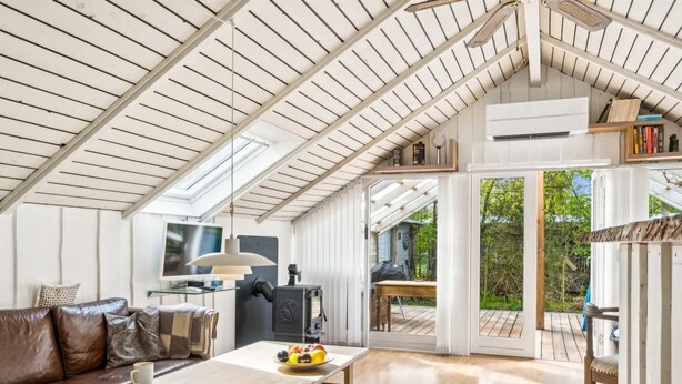 A spacious loft with a high ceiling, a cozy seating area, a dining table, and a view of the outdoors.