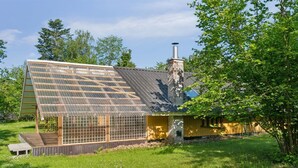 A house with a sloped roof, a chimney, and a large window.