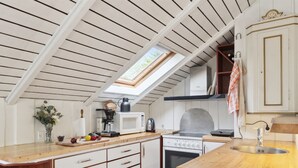A compact kitchen with a skylight, white cabinets, and a wooden countertop.